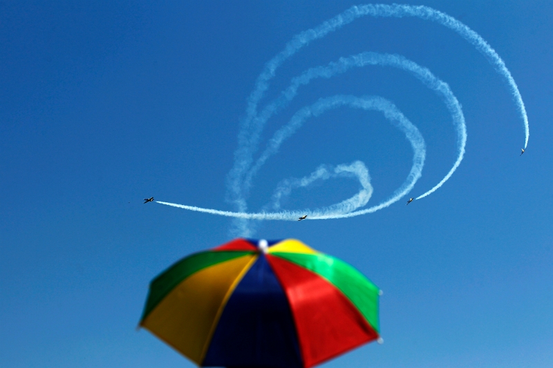 Bogdan Cristel - Gânduri.jpg - A man under an umbrella watches Latvia's Baltic Bees aerobatic team performing on L-39C Albatross airplanes during Bucharest International Air Show at Baneasa airport July 27, 2013. REUTERS/Bogdan Cristel (ROMANIA - Tags: TRANSPORT SOCIETY TPX IMAGES OF THE DAY) - RTX121IK